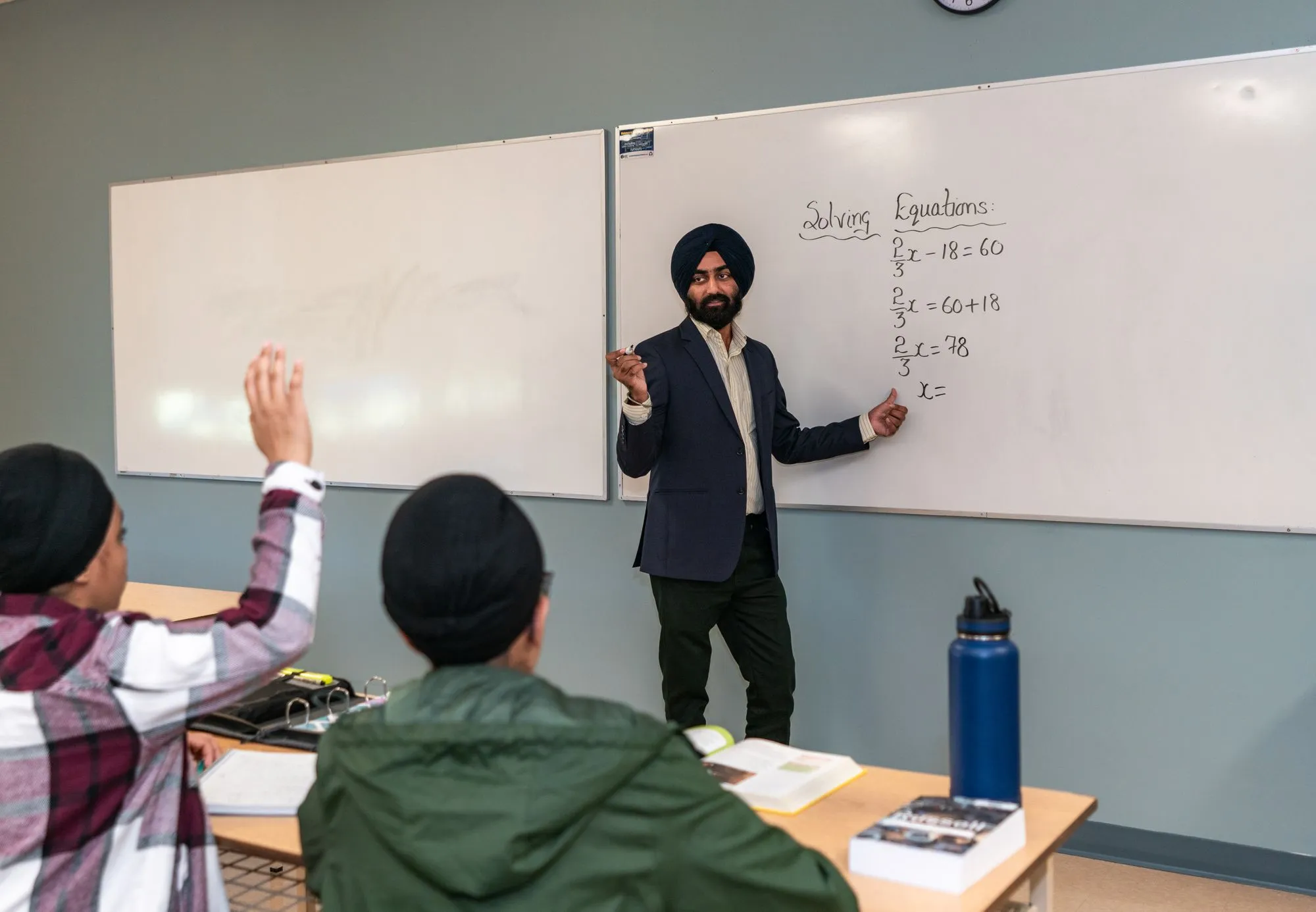 A teacher solving equations on a whiteboard for a class